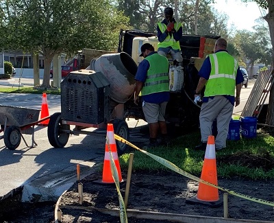 publix works maintenance workers making Sidewalk repair at Park Blvd N & Barcelona Ave  area blocked off by orange and while coness and caution tape