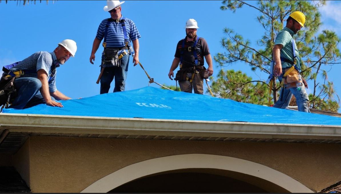 Roofers working on blue tarp